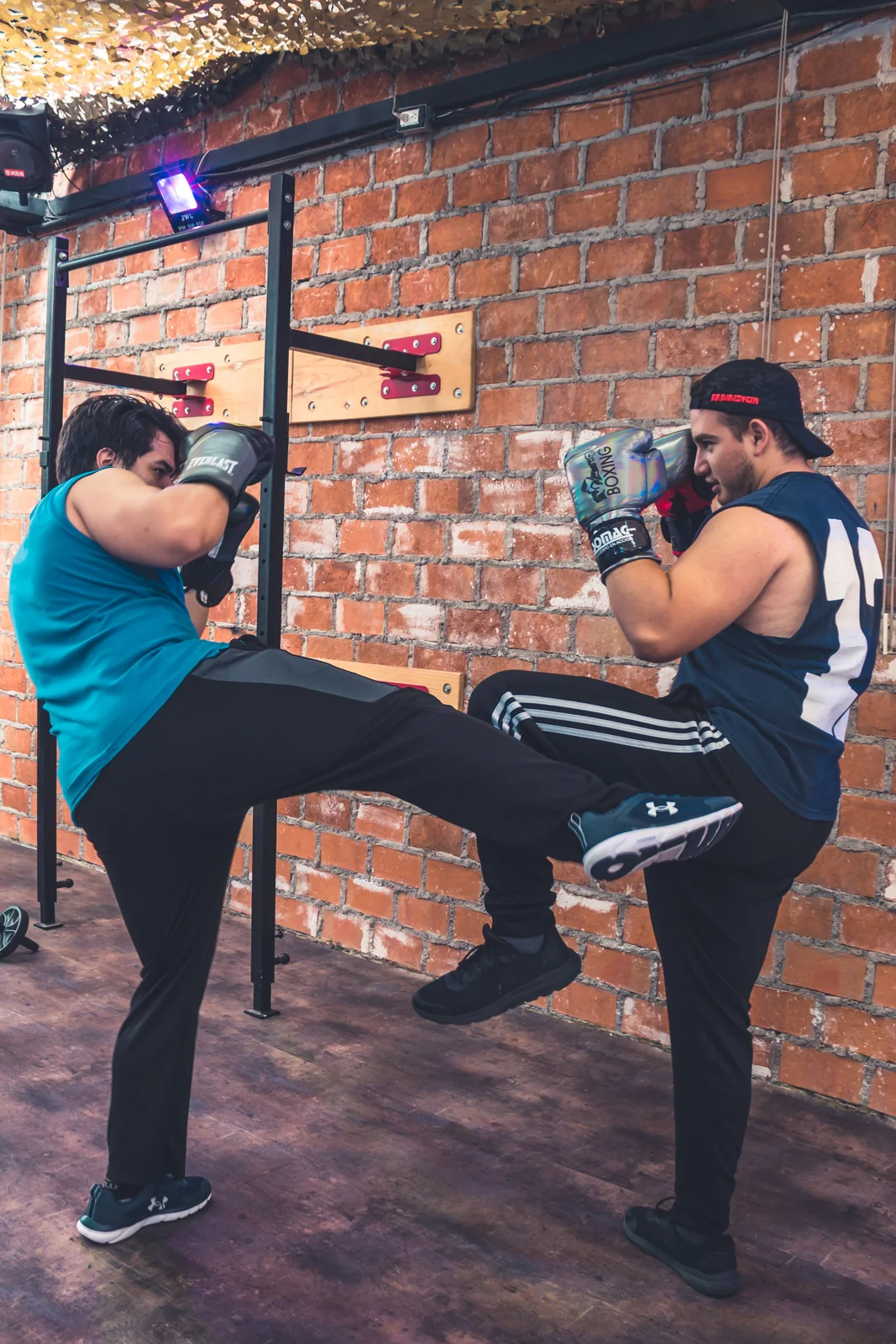 Twee trainingspartners oefenen een kickbokstechniek.