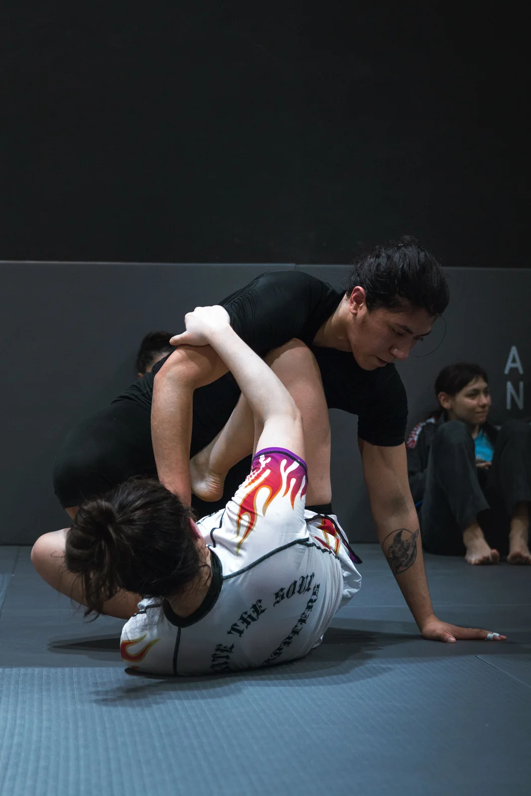 Twee MMA-beoefenaars werken aan controle tijdens een grondoefening.