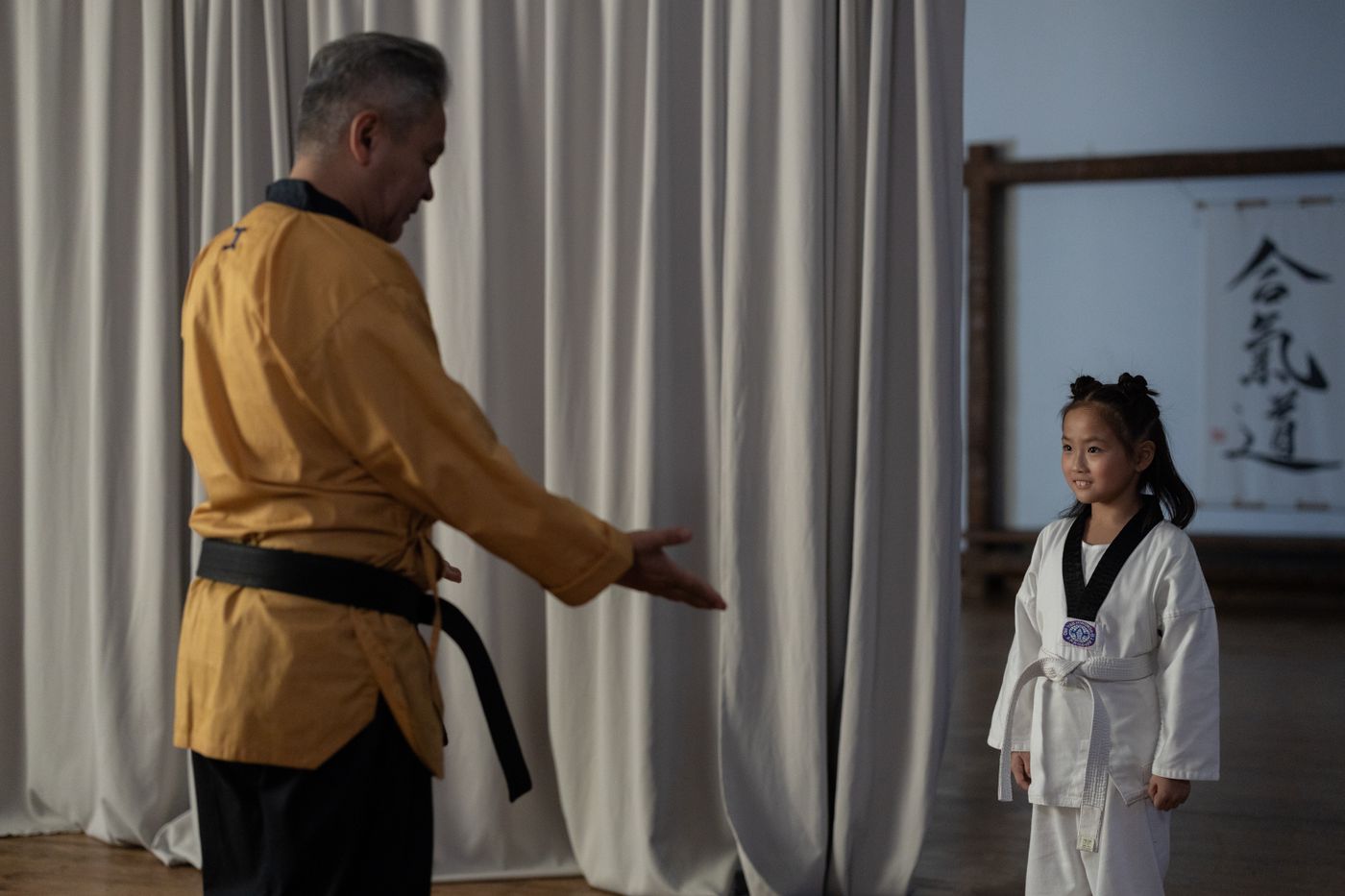 Een instructeur begeleidt een kind tijdens een vechtsportles